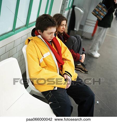 Young man and young woman sitting next to each other on subway platform, outside View Large Photo Image Stock Image - Young man and young woman sitting next to each other on subway platform, outside. Fotosearch