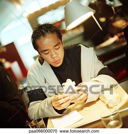 Young man eating sandwich at table, close-up View Large Photo Image Stock Image - Young man eating sandwich at table, close-up. Fotosearch
