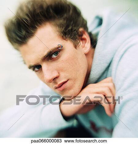 Young man resting chin on hand, looking at camera, portrait. View Large Photo Image Stock Image - Young man resting chin on hand, looking at camera, portrait.. Fotosearch