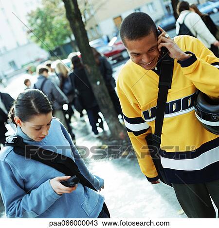 Young man talking on cell phone next to young woman dialing cell phone outside. View Large Photo Image Stock Image - Young man talking on cell phone next to young woman dialing cell phone outside.. Fotosearch