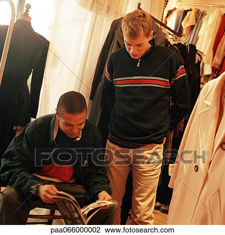 Young men looking at magazine in store. View Large Photo Image Stock Image - Young men looking at magazine in store. . Fotosearch