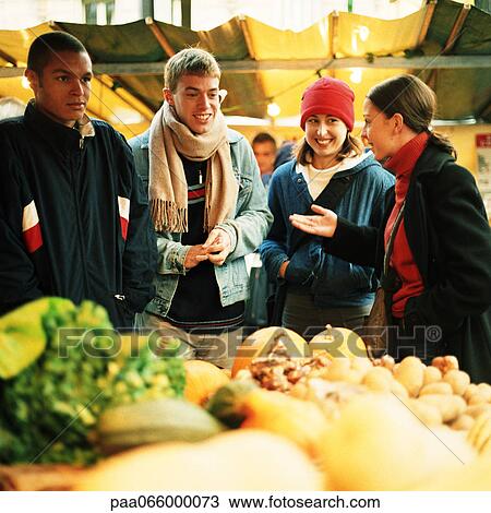 Young people at produce market, fruits and vegetables blurred in foreground View Large Photo Image Stock Image - Young people at produce market, fruits and vegetables blurred in foreground. Fotosearch