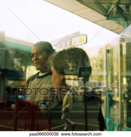 Young people seen through window with reflections, outside at bus station View Large Photo Image Stock Photo - Young people seen through window with reflections, outside at bus station. Fotosearch