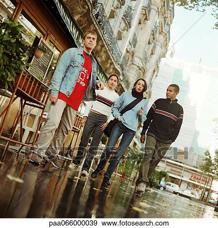 Young people walking together outside near cafe, full length View Large Photo Image Stock Photo - Young people walking together outside near cafe, full length. Fotosearch