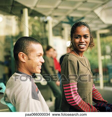 Young woman and young man sitting together at bus station View Large Photo Image Picture - Young woman and young man sitting together at bus station. Fotosearch