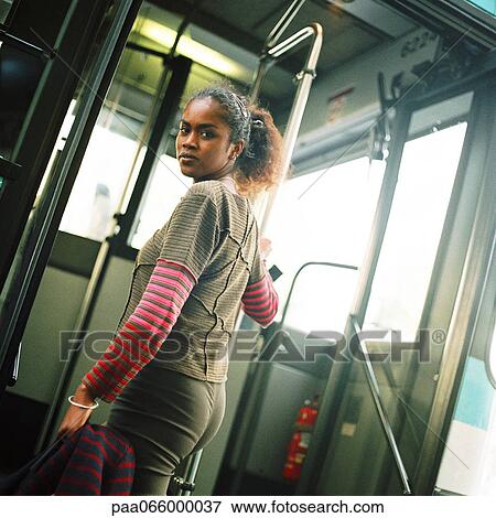 Young woman holding rail, getting on bus, looking back over shoulder View Large Photo Image Stock Photo - Young woman holding rail, getting on bus, looking back over shoulder. Fotosearch