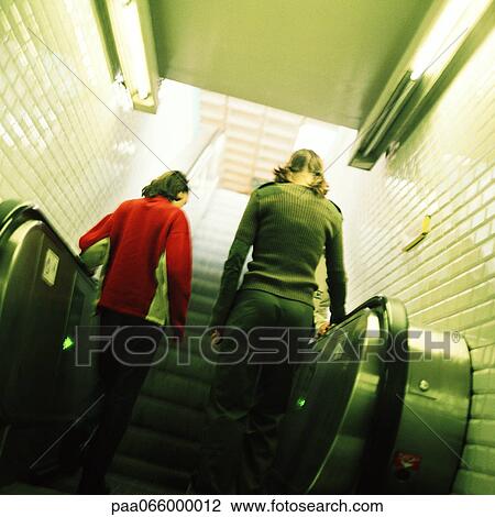 Young women going up escalator, rear view View Large Photo Image Stock Image - Young women going up escalator, rear view. Fotosearch