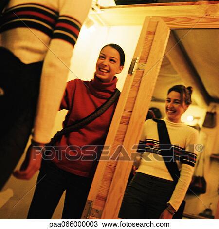 Stock Image - Young women laughing together in shop, low angle view. Fotosearch