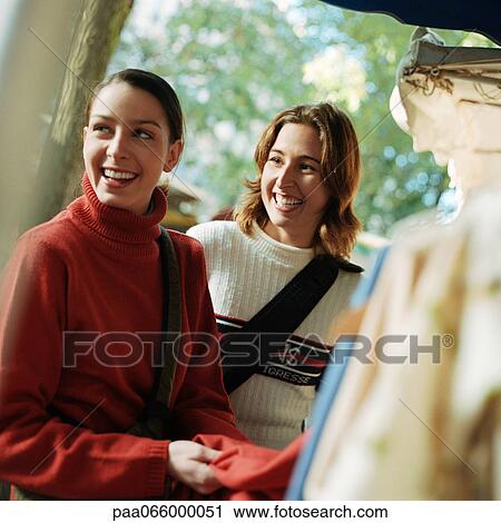 Young women smiling next to rack of clothing, outdoors View Large Photo Image Stock Image - Young women smiling next to rack of clothing, outdoors. Fotosearch
