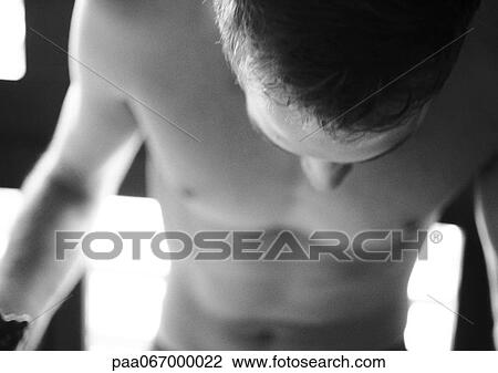 Stock Image - Barechested man looking down, close-up, black and white.. Fotosearch