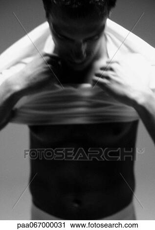 Stock Image - Man putting shirt on, blurred, close-up, black and white.. Fotosearch