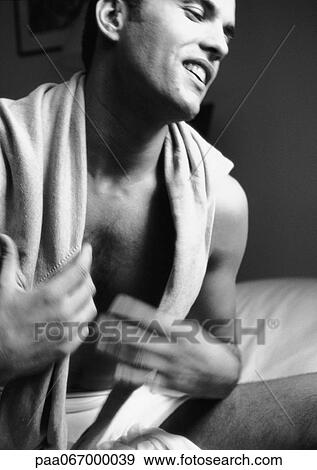 Stock Photo - Man sitting on bed with shirt over shoulders, close-up, black and white.. Fotosearch