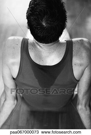 Man sitting on floor, wearing sweaty tanktop, high angle rear view, black and white. View Large Photo Image Stock Image - Man sitting on floor, wearing sweaty tanktop, high angle rear view, black and white.. Fotosearch