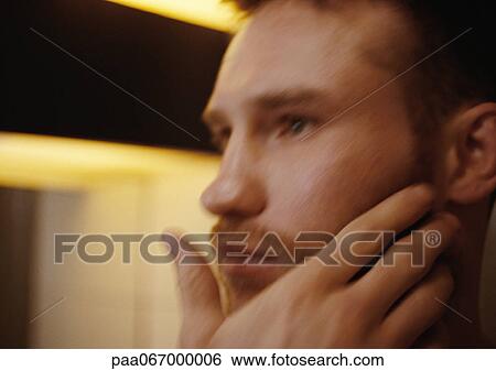 Stock Photograph - Man touching face, side view, close-up, blurred.. Fotosearch