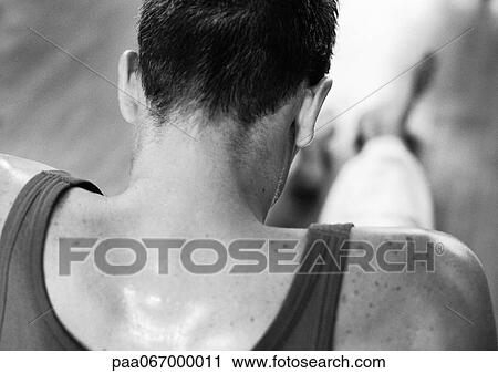 Stock Image - Man wearing tanktop, head and shoulders, rear view, black and white.. Fotosearch