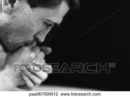 Stock Image - Man with hands to mouth, close-up, black and white.. Fotosearch