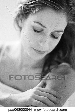 Picture - Woman looking down, touching arm, portrait, close-up, black and white.. Fotosearch