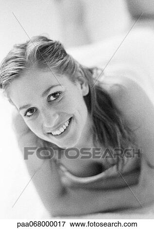 Woman lying on bed, leaning on arms, smiling at camera, black and white. View Large Photo Image Stock Photo - Woman lying on bed, leaning on arms, smiling at camera, black and white.. Fotosearch