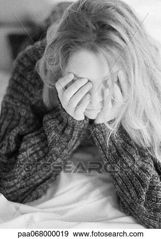 Stock Photo - Woman lying on bed, leaning on elbows, hands over face, black and white.. Fotosearch
