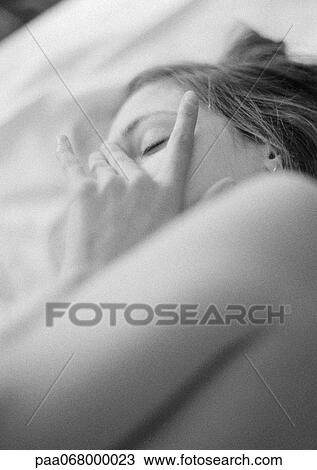 Stock Image - Woman lying on bed, touching face, close-up, black and white.. Fotosearch