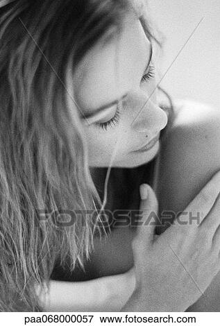 Stock Photo - Woman touching arm and looking down, close-up, black and white.. Fotosearch