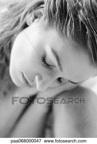 Stock Photo - Woman with eyes closed leaning head on knee, close-up of face, black and white.. Fotosearch