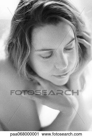 Stock Image - Woman with eyes closed resting chin on hand, black and white.. Fotosearch