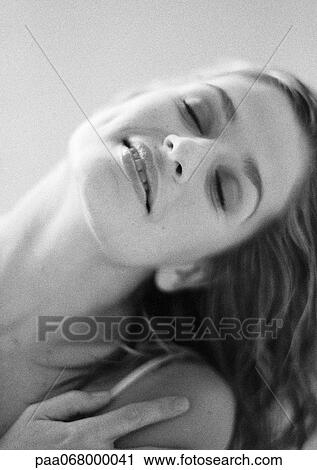 Stock Image - Woman with eyes closed tilting head and touching shoulder, portrait, close-up, black and white.. Fotosearch
