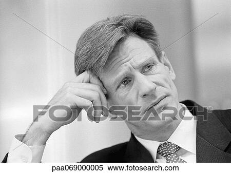 Businessman leaning head on hand and furrowing brow, close-up, black and white. View Large Photo Image Stock Photography - Businessman leaning head on hand and furrowing brow, close-up, black and white.. Fotosearch