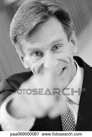 Businessman pointing at camera, hand blurred in foreground, black and white, close-up, portrait. View Large Photo Image Stock Photo - Businessman pointing at camera, hand blurred in foreground, black and white, close-up, portrait.. Fotosearch
