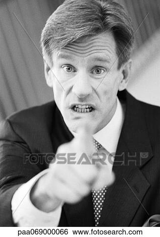 Stock Photograph - Businessman pointing at camera, hand blurred in foreground, black and white, portrait.. Fotosearch