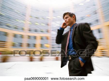 Businessman talking on cell phone, outside, building in background, blurred. View Large Photo Image Stock Image - Businessman talking on cell phone, outside, building in background, blurred.. Fotosearch