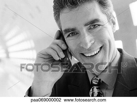 Businessman talking on cellular phone smiling at camera, close-up. View Large Photo Image Stock Image - Businessman talking on cellular phone smiling at camera, close-up.. Fotosearch