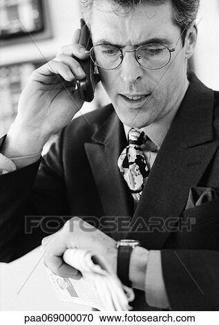Businessman talking on cellular phone, checking time, head and shoulders, b&w. View Large Photo Image Stock Image - Businessman talking on cellular phone, checking time, head and shoulders, b&w.. Fotosearch