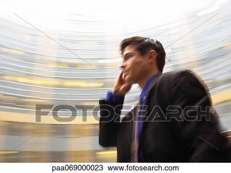 Businessman using cell phone, waist up, building in background, low angle view, blurred View Large Photo Image Stock Image - Businessman using cell phone, waist up, building in background, low angle view, blurred. Fotosearch