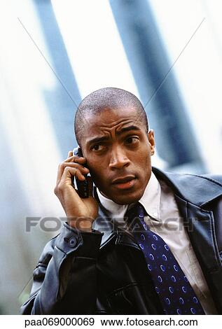Stock Photo - Businessman using cellular phone and furrowing brow, portrait.. Fotosearch