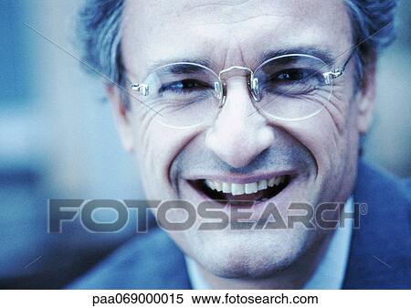 Stock Photography - Businessman wearing glasses, smiling at camera, close-up. Fotosearch