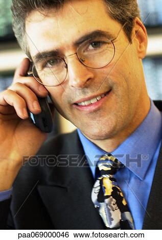 Stock Photograph - Businessman wearing glasses using cellular phone, close-up, portrait.. Fotosearch