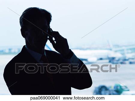 Man wearing suit, holding cell phone to ear, silhouette, airplanes in background. View Large Photo Image Stock Image - Man wearing suit, holding cell phone to ear, silhouette, airplanes in background.. Fotosearch
