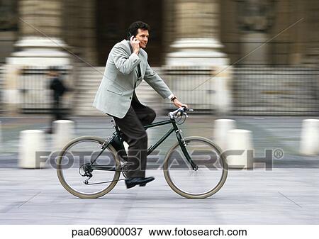 Man wearing suit, holding cell phone to ear and riding bike, blurred. View Large Photo Image Stock Photo - Man wearing suit, holding cell phone to ear and riding bike, blurred.. Fotosearch