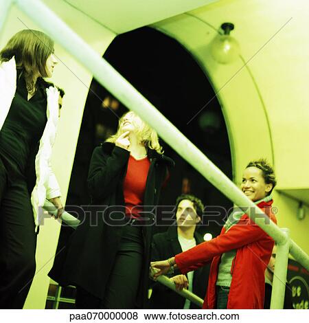 Stock Photo - Group of people, low angle view, rail in foreground. Fotosearch