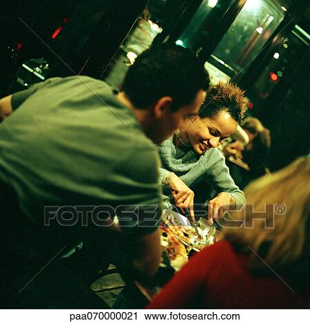 Group of young people sitting at table in restaurant View Large Photo Image Stock Image - Group of young people sitting at table in restaurant. Fotosearch