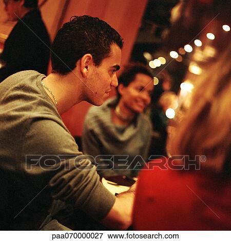 Stock Photo - Group of young people sitting at table in restaurant. Fotosearch