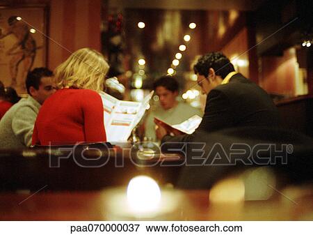 Group of young people sitting in restaurant looking at menus View Large Photo Image Stock Photo - Group of young people sitting in restaurant looking at menus. Fotosearch