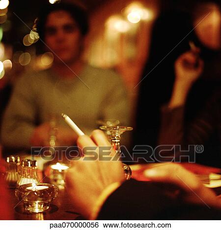 Hand holding cigarette, people blurred in background View Large Photo Image Stock Photograph - Hand holding cigarette, people blurred in background. Fotosearch