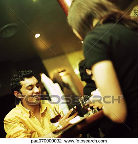Young man and woman sitting at table in restaurant, both holding cellphones View Large Photo Image Stock Image - Young man and woman sitting at table in restaurant, both holding cellphones. Fotosearch