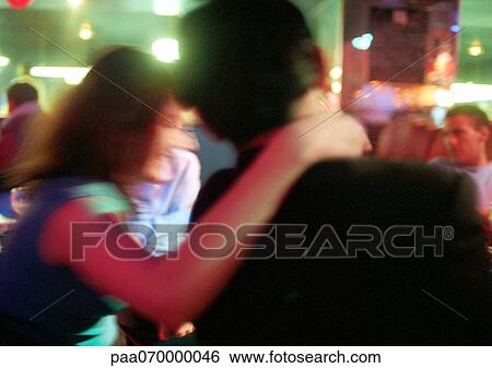 Young man and woman talking in bar, woman with hand around man's neck, blurred View Large Photo Image Stock Photograph - Young man and woman talking in bar, woman with hand around man's neck, blurred. Fotosearch