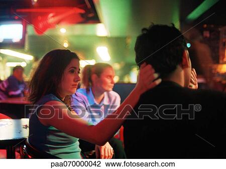 Stock Image - Young man and young woman sitting in bar. Fotosearch