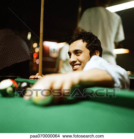 Young man retrieving balls from pool table. View Large Photo Image Picture - Young man retrieving balls from pool table.. Fotosearch