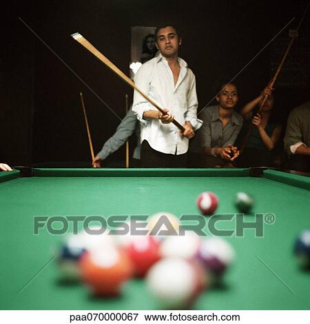 Young man shooting pool, people watching in background, billiard balls blurred in foreground View Large Photo Image Stock Photo - Young man shooting pool, people watching in background, billiard balls blurred in foreground. Fotosearch